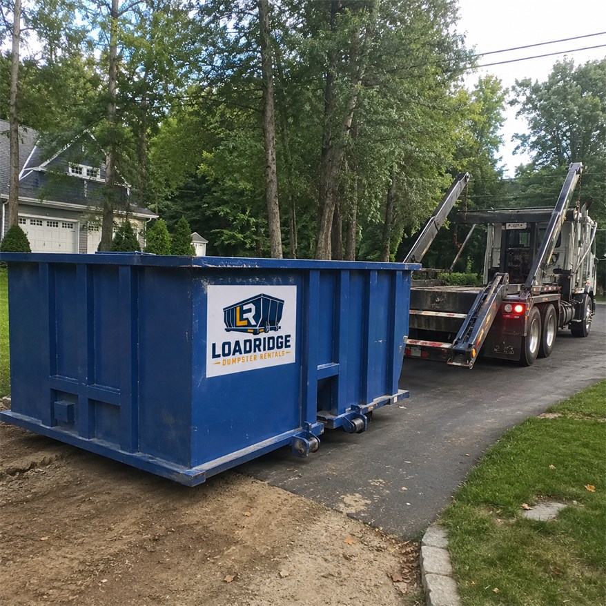 Blue Loadridge roll-off dumpster and delivery truck at a residential cleanup site in Redwood City